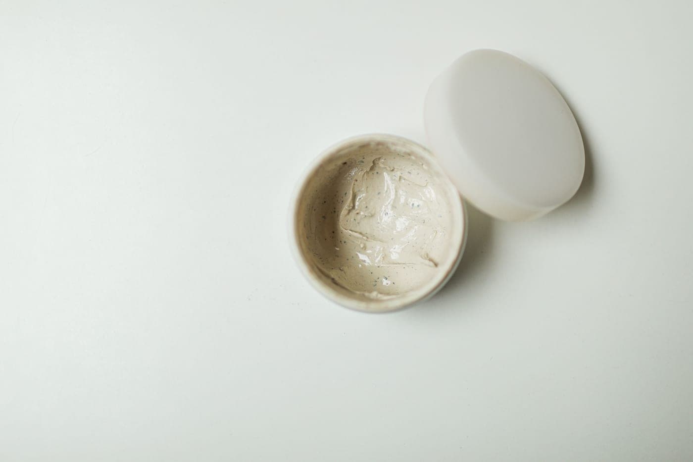 A warm, minimal still-life of skincare cream jars on a neutral background